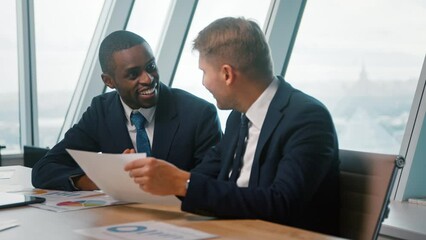 Wall Mural - Smiling male colleagues discussing a new project in the office. Business people at a meeting