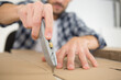 man using an utility knife to open a cardboard box