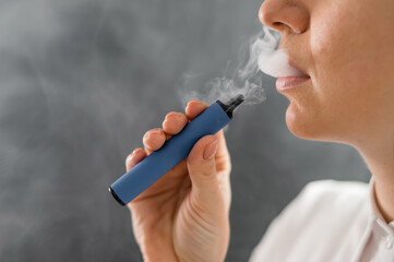 Caucasian woman smokes a disposable vape in the studio.