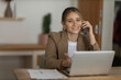 © Buonaventura - Young woman working at home with laptop and papers on desk. Home office concept.