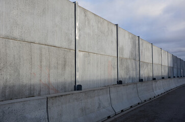 soundproof wall made of concrete porous ribbed material. fence of gray blocks embedded in metal beams, on street. road traffic noise  garden and residential area. protection of Jerusalem, rocket