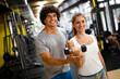 © NDABCREATIVITY - Fit happy woman with her personal fitness trainer in the gym exercising with dumbbells