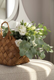Fototapeta Tulipany - Stylish wicker basket with bouquet of flowers on ottoman in room