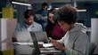 © TommyStockProject - African-American female entrepreneur work on laptop and chat on smartphone in office.