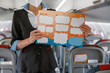 © Kostiantyn - Stewardess with paper booklet standing in aircraft passenger salon