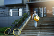 © blackday - Express delivery courier with insulated bag going up the stairs after parking bicycle.
