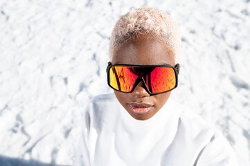 A African American woman with sunglasses sitting on snowy ground during winter