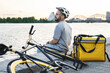 © blackday - Express delivery courier sitting on quay looking at river.