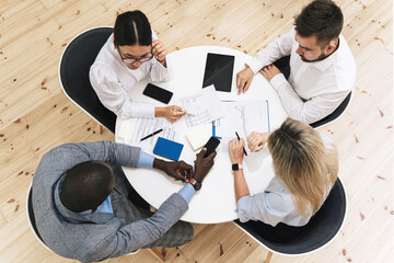 Multi-ethnic business people during meeting in modern office sitting at the round table