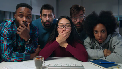 Multiethnic startup team looking at computer screen and getting shocked