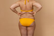 Cropped image of overweight fat woman back with obesity, excess fat in yellow swimsuit. Big size. Holding waist flabs, visceral, cellulite. Varicose veins, imperfection skin puffy body. Liposuction