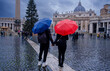 Young couple under umbrellas standing near St Peter's basilica at Vatican. Holidays for couple in Italy