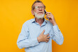 © Tatiana - Senior grey-haired man gray beard with glasses talking on the phone isolated background