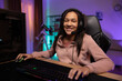 © ABCreative - Portrait of a smiling young gamer, the girl is happy to win the game, pass the level, the teenager has a headset, professional gaming accessories, the room lit by fioket blue led lights