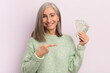 © kues1 - middle age woman smiling cheerfully, feeling happy and pointing to the side. dollar banknotes concept