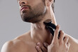 © Drobot Dean - Young man shaving beard with electric razor