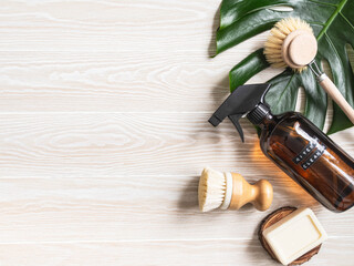 Amber bottle with washing solution, brush and soap on white wood table.