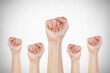 Many clenched fists punch air energetically on gray background. Together we stand !