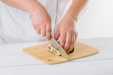 Wall Mural - the chef prepares sushi and cuts them with a knife