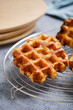A vertical shot of Belgian waffles from the city of Liege on round steel trivet