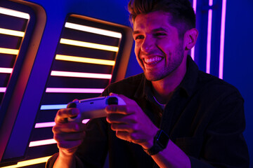 Young bristle man laughing while playing video game with joystick