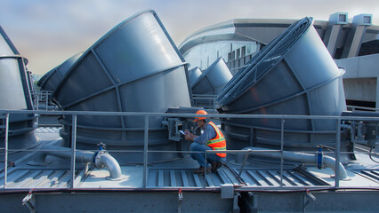 Engineer under checking the industry cooling tower air conditioner is water cooling tower air chiller HVAC of large industrial building to control air system.