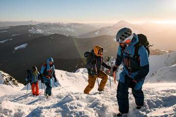 group of male tourists climbing up at snow-covered mountain trail against the backdrop of a beautifu