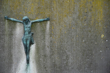 Very old bronze statue patinated by the years on a weathered concrete background