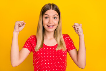 Poster - Photo of delighted positive girl raise fists celebrate luck toothy smile isolated on yellow color background