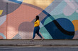 © Cultura Creative - UK, South Yorkshire, Woman with braided hair walking by colorful wall