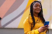 UK, South Yorkshire, Portrait Of Woman With Braided Hair Holding Smart Phone
