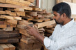 © WESTOCK - Focus on hand, Back view of carpenter selecting or searching best wood for making furniture at workshop - concept of quality assurance, small business and woodworking.