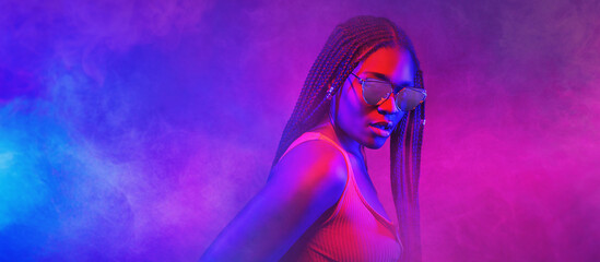 Wall Mural - Portrait of fashion young girl in cool sunglasses in red and blue neon light in the studio