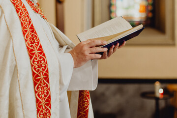 les mains du prêtre lisant la Bible