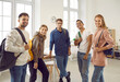© Studio Romantic - Group of happy diverse fellow students. Indoor portrait of five positive mixed race multiethnic college or university friends with backpacks standing in modern classroom, smiling and looking at camera