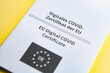 Close up of an EU Digital Covid 19 Certificate on yellow background, vaccination against corona virus