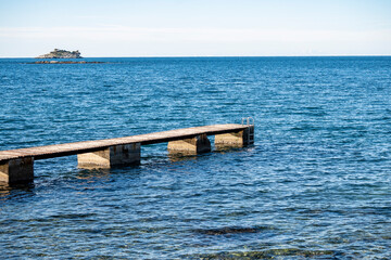 Canvas Print - Wooden pier on the Rovinj city beach, with view on the distant island and open, Adriatic sea