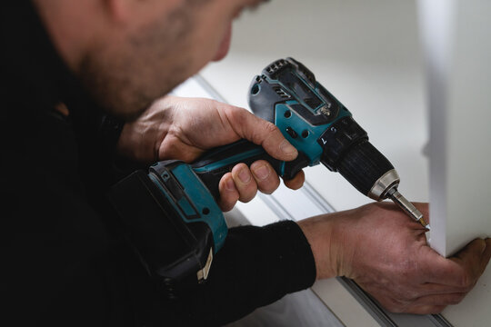 One man caucasian male using electric cordless screwdriver drill assembling furniture at home DIY carpenter at work