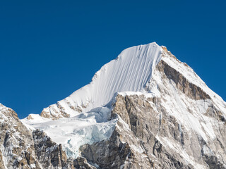 Wall Mural - alone snow peak with giant steep wall under blue sky in nepal