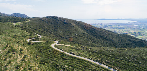 Wall Mural - Empty long mountain road to the horizon on a sunny summer day at bright sunset - aerial drone shot