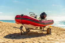 Red Rubber Motorboat Stands On The Sandy Seashore 