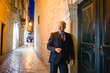 eleganter Mann im Anzug lehnt am Tor, abends in Altstadt-Gasse