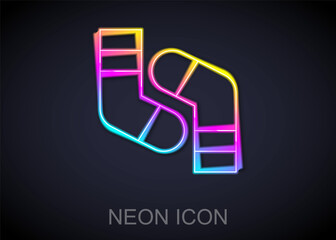 Sticker - Glowing neon line Socks icon isolated on black background. Vector