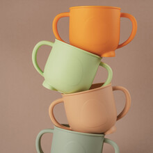 Modern Colorful Pastel Silicone Cups Stacked In Column On Brown Background. Baby Tableware, First Feeding, Serving Concept. Instagram Use, Square Frame, Levitation.