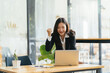 © PaeGAG - Excited young woman standing at table with laptop and celebrating success