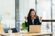 © PaeGAG - Excited young woman standing at table with laptop and celebrating success
