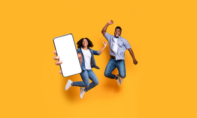 Wall Mural - Black couple showing white empty smartphone screen and jumping