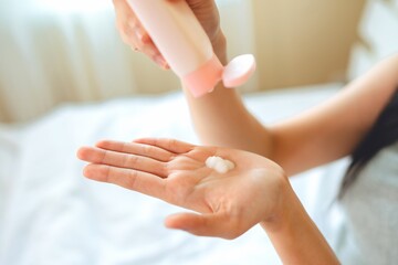 asian woman use lotion hands cream moisture and white moisturize lotion on bed in bedroom, therapy beauty, skin care concept.