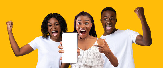 Happy black guy, two ladies showing smartphone with empty screen