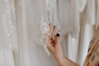 Closeup of a woman looking at a wedding dress, touching gown sleeve manually embroidered, at a wedding showroom.